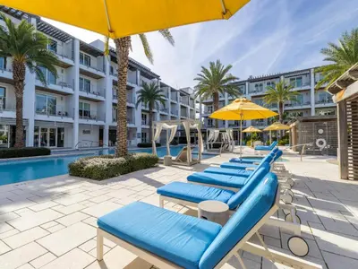a row of lounge chairs with umbrellas and a pool at The Pointe on 30A #334 in Rosemary Beach