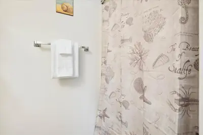 a bathroom with a shower curtain with drawings of leaves at Gulf Highlands 219 by Book That Condo in Panama City Beach