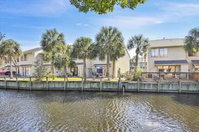 a building next to a river with palm trees at Gulf Highlands 219 by Book That Condo in Panama City Beach