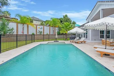 a swimming pool with chairs and umbrellas next to a house at SOUTHERN SEABREEZE 5BR POOL & BEACH by Barclé in Rosemary Beach