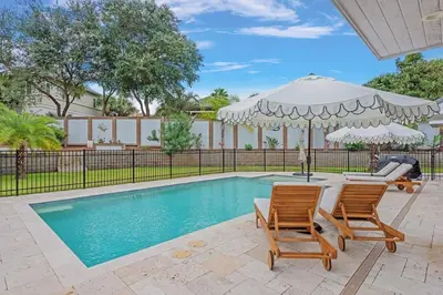 a swimming pool with two chairs and an umbrella at SOUTHERN SEABREEZE 5BR POOL & BEACH by Barclé in Rosemary Beach
