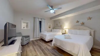 a bedroom with two beds and a flat screen tv at Tidewater 0401 in Panama City Beach