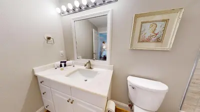 a bathroom with a sink and a toilet and a mirror at Tidewater 0401 in Panama City Beach