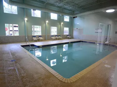 a swimming pool in a building with tables and chairs at Tidewater 0401 in Panama City Beach