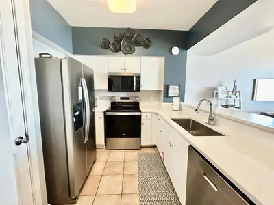 a kitchen with white cabinets and a stainless steel refrigerator at Amazing views! Great beachfront Panama City Condo in Panama City Beach