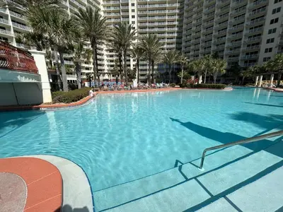 a large swimming pool with palm trees and buildings at Amazing views! Great beachfront Panama City Condo in Panama City Beach