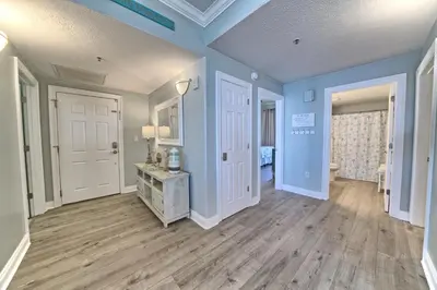 a living room with blue walls and wooden floors at Oceanfront Retreat with Panoramic Views - 0301 condo in Panama City Beach