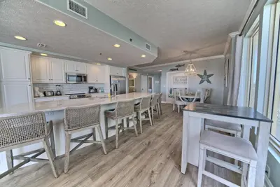 a kitchen with a bar with chairs and a table at Oceanfront Retreat with Panoramic Views - 0301 condo in Panama City Beach