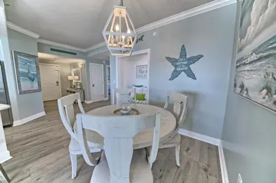 a dining room with a white table and chairs at Oceanfront Retreat with Panoramic Views - 0301 condo in Panama City Beach