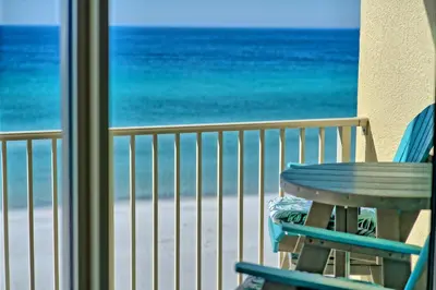 a table and chairs on a balcony overlooking the beach at Oceanfront Paradise with Pool Access - 0606 condo in Panama City Beach