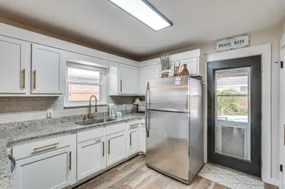 a kitchen with white cabinets and a stainless steel refrigerator at Panama City Beach Home with Private Pool and Gas Grill in Panama City Beach