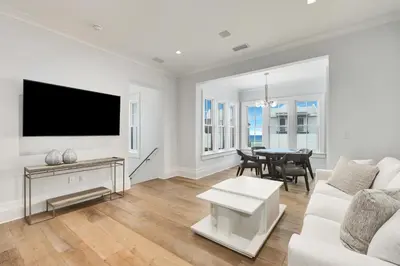 a living room with a white couch and a tv at Seaclusion at Seagrove in Santa Rosa Beach