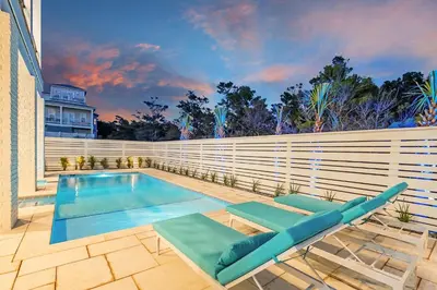 a swimming pool with two lounge chairs next to a fence at Emerald Palms in Inlet Beach