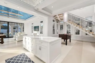 a white kitchen with a staircase and a living room at Sanctuary at Seagrove in Santa Rosa Beach
