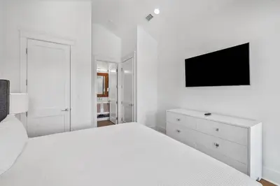 a white bedroom with a white bed and a tv at Casa al Mare in Santa Rosa Beach