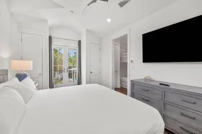 a white bedroom with a large bed and a flat screen tv at Casa al Mare in Santa Rosa Beach