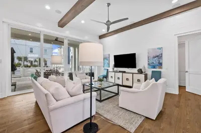 a living room with white furniture and a flat screen tv at Seagrove Sparrow in Santa Rosa Beach