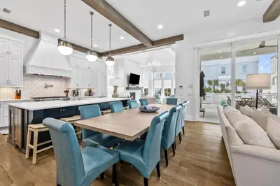 a kitchen and dining room with a wooden table and blue chairs at Seagrove Sparrow in Santa Rosa Beach