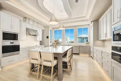 a kitchen with white cabinets and a table with chairs at Soleil at Seagrove in Santa Rosa Beach