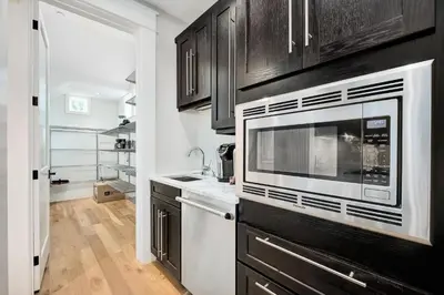 a kitchen with black cabinets and a microwave at St. Ivory in Rosemary Beach