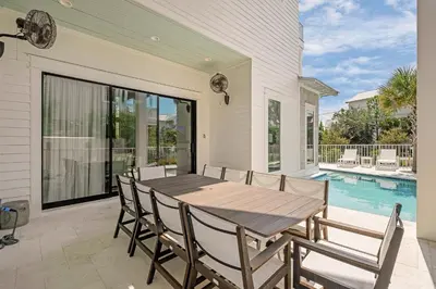 a dining room with a table and chairs and a swimming pool at Coastal Dream in Santa Rosa Beach