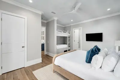 a white bedroom with a bed and a flat screen tv at Coastal Dream in Santa Rosa Beach