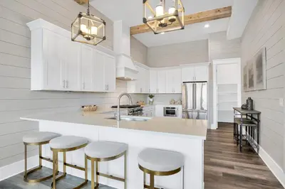 a kitchen with white cabinets and bar stools at Aces High in Santa Rosa Beach