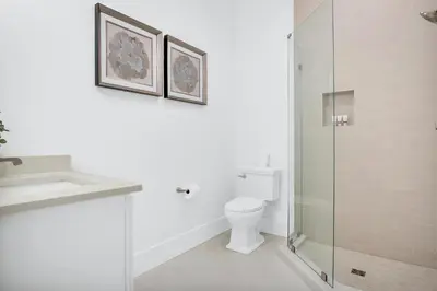 a white bathroom with a toilet and a glass shower at Aces High in Santa Rosa Beach