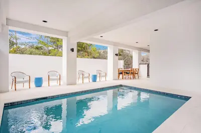 a swimming pool in a house with chairs and a table at Aces High in Santa Rosa Beach