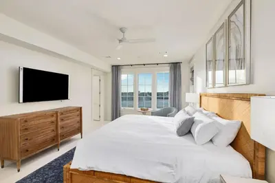 a white bedroom with a large bed and a flat screen tv at Emerald Le Luxe in Inlet Beach