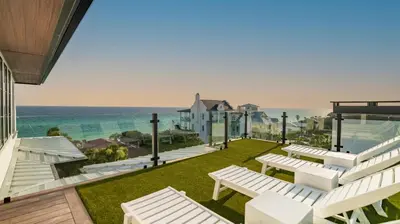 a patio with white chairs and a view of the ocean at Above & Beyond in Santa Rosa Beach