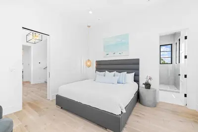 a white bedroom with a bed and a bathroom at Above & Beyond in Santa Rosa Beach