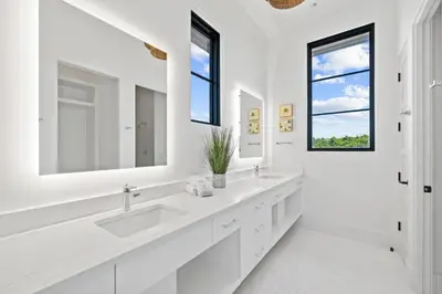 a white bathroom with two sinks and two windows at Above & Beyond in Santa Rosa Beach