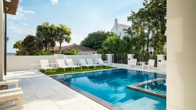 a swimming pool with white chairs and a swimming pool at Above & Beyond in Santa Rosa Beach