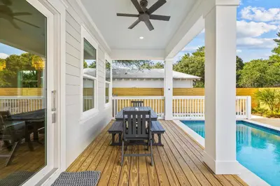 a screened porch with a table and a pool at Idyll Time in Santa Rosa Beach