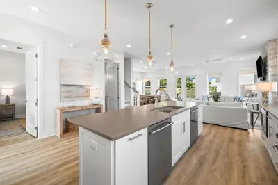 a kitchen and living room with white walls and wood floors at Idyll Time in Santa Rosa Beach