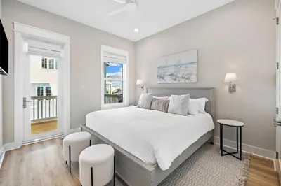 a white bedroom with a large bed and two stools at Idyll Time in Santa Rosa Beach