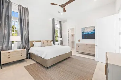 a white bedroom with a bed and a large window at Bullish On Beaches in Inlet Beach