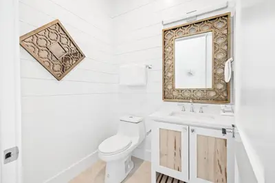 a white bathroom with a toilet and a mirror at Bullish On Beaches in Inlet Beach