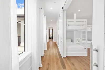 a room with white bunk beds and a hallway at Bullish On Beaches in Inlet Beach