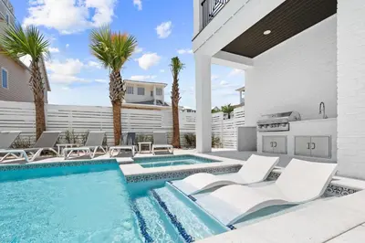 a swimming pool with white chairs and palm trees at Bullish On Beaches in Inlet Beach