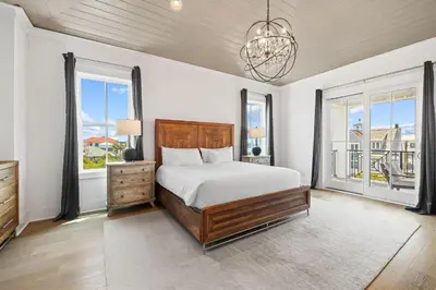 a bedroom with a bed and two windows and a chandelier at Seven Palms Retreat in Inlet Beach