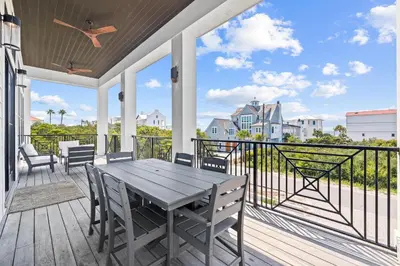 a patio with a wooden table and chairs on a balcony at Seven Palms Retreat in Inlet Beach
