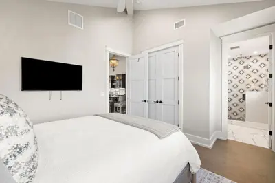 a white bedroom with a bed and a flat screen tv at Emerald View in Inlet Beach
