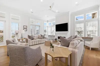 a living room with white furniture and a flat screen tv at Good Vibrations in Santa Rosa Beach
