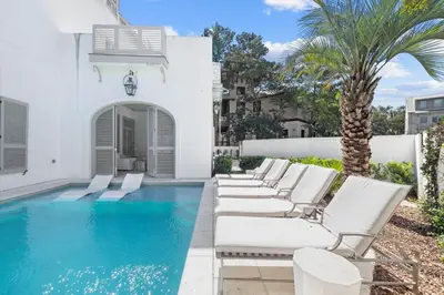 a row of white lounge chairs next to a swimming pool at Playa Blanca in Rosemary Beach