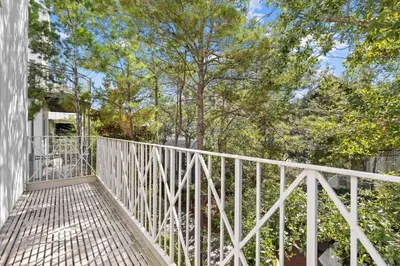 a white railing on a porch with trees in the background at Playa Blanca in Rosemary Beach