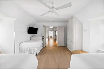 a white bedroom with two beds and a ceiling fan at Playa Blanca in Rosemary Beach