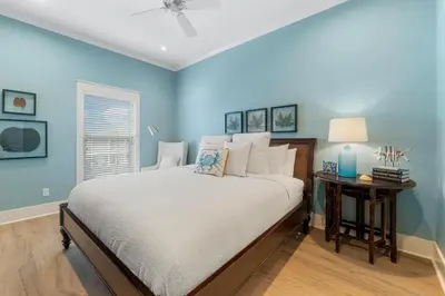 a blue bedroom with a bed and a table with a lamp at Beach Please Beach House by Panhandle Getaways in Panama City Beach