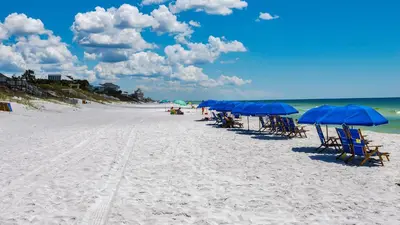 a group of chairs and umbrellas on a beach at Villas at Seagrove A101 - Sunshine Sabbatical in Santa Rosa Beach